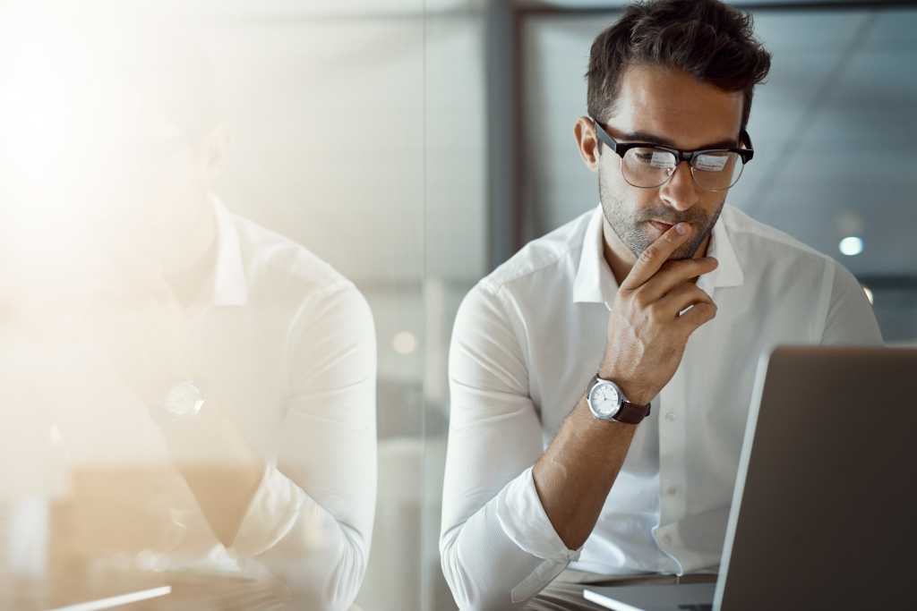 Cropped shot of a young businessman looking thoughtful while working on his laptop in the o