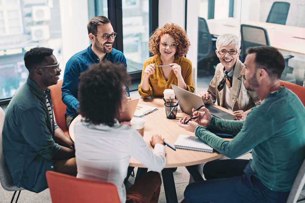 Mixed group of business people sitting around a table talking