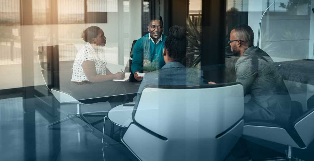 Team of african-american bussines people talking during an work meeting shot through a glass window, looking into the boardroom