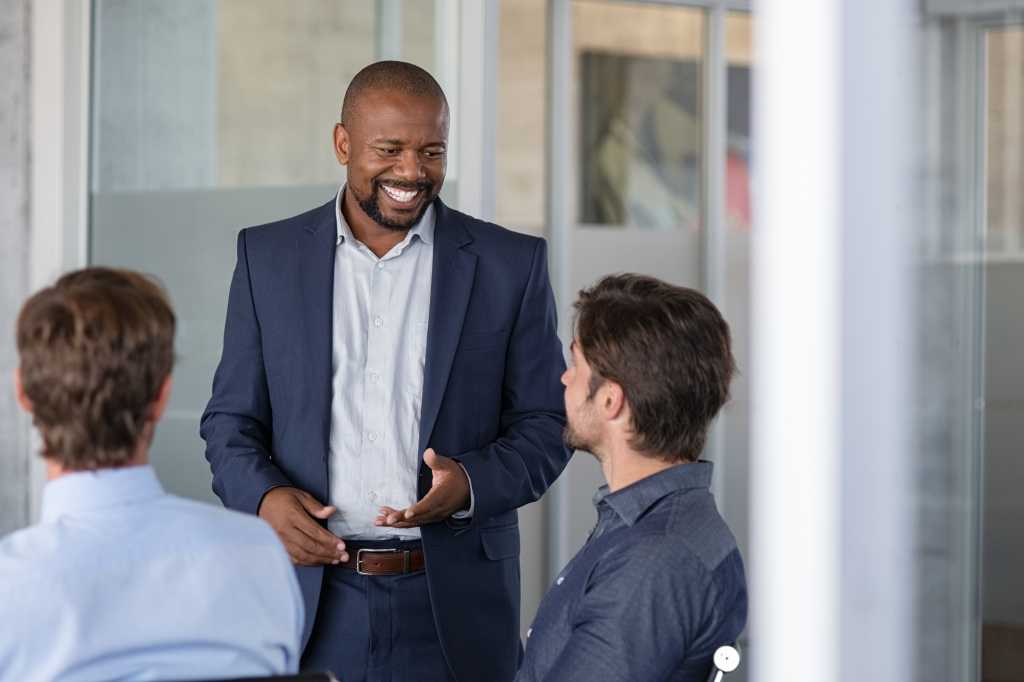 Group of business people brainstorming together in meeting room. Business colleagues discussing a new business strategy plan. Successful african american businessman doing presentation to his partners