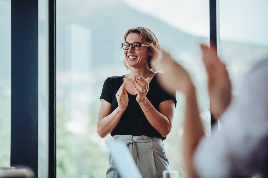 Businesswoman clapping hands after successful brainstorming session in boardroom. Business people women applauding after productive meeting.