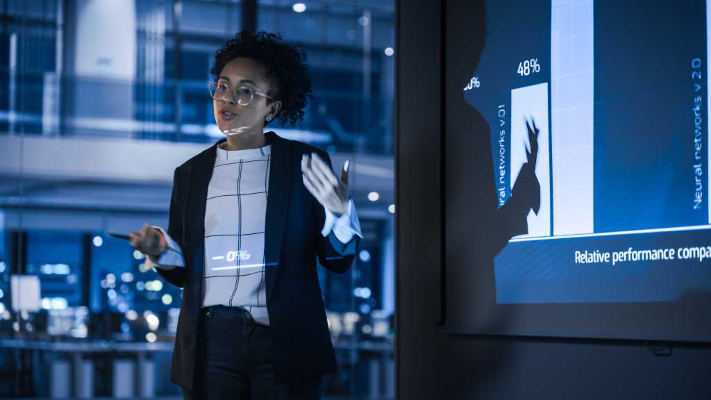 e-Business Technology Conference Presentation: Innovative Black Tech Engineer Talks about Revolutionary High-Tech Product. Projector Screen Shows Graphs, Infographics, AI, Big Data, Machine Learning