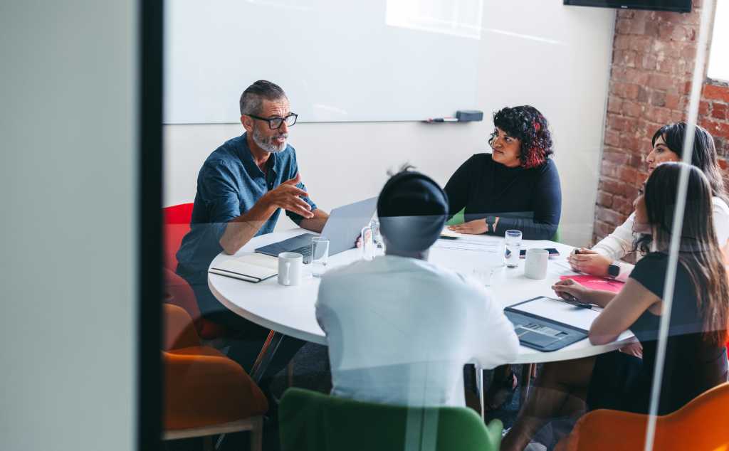 Experienced mature businessman briefing his colleagues in a meeting. Businesspeople having a discussion in a modern workplace. Group of creative businesspeople working as a team.