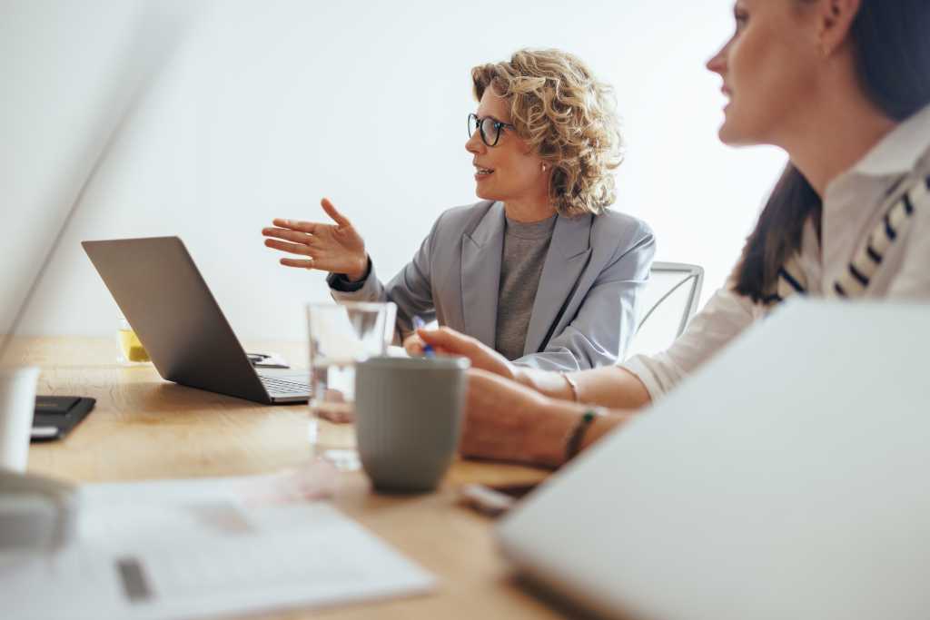 Mature business woman discussing a project with her team in an office. Creative business people having a meeting in a boardroom. Business team working together in an advertising agency.