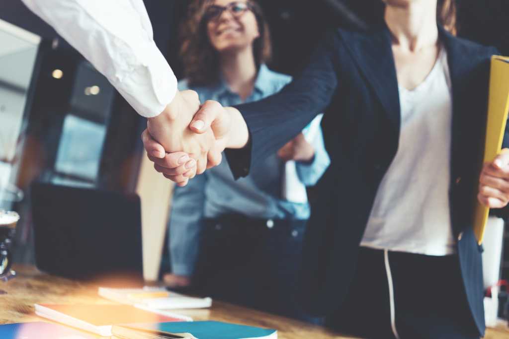 negoation Young business people shaking hands in the office. Finishing successful meeting. Three persons