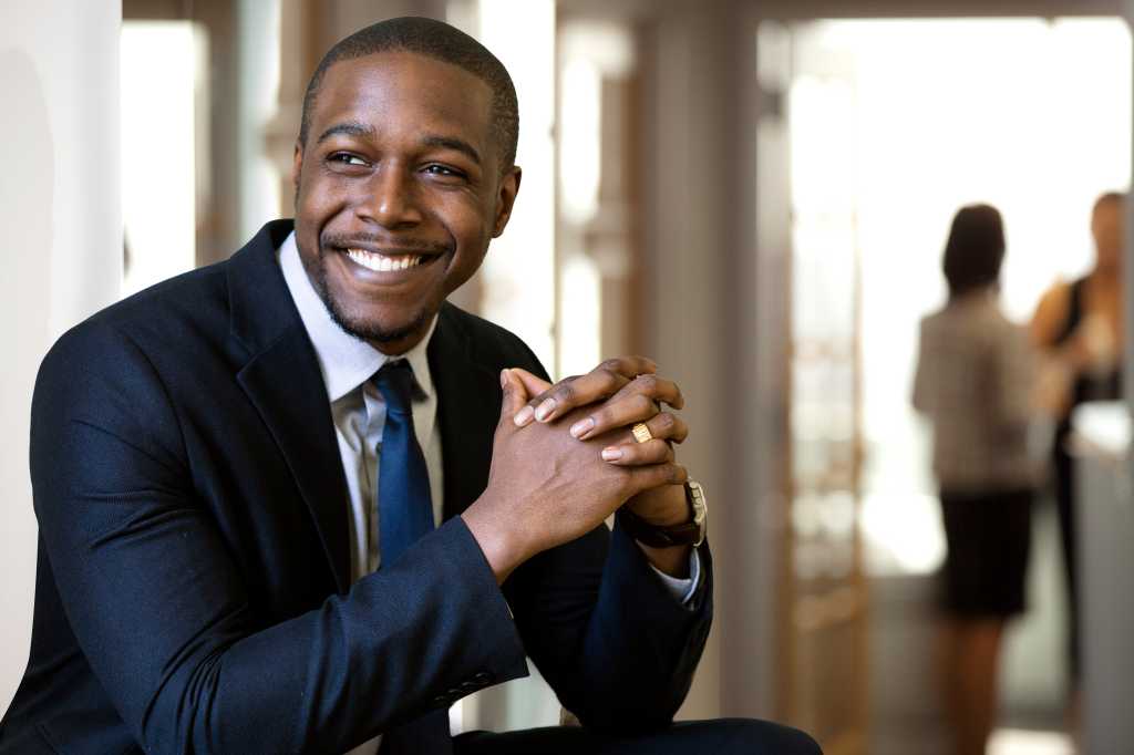 Enthusiastic chic handsome charismatic classy african american CEO in his office smiling confidently